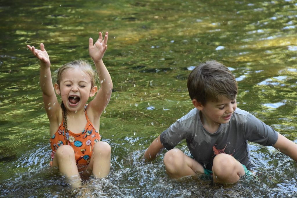 Kids splashing and playing in Brushy Creek at Redbud Ranch RV Resort in Hutto, Texas